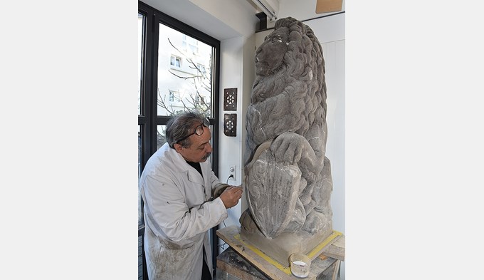 Bildhauer Vitus Wey bessert die wieder zutage getretenen Schäden am Sandstein-Löwen von Paul Amlehn aus. (Foto Daniel Zumbühl)