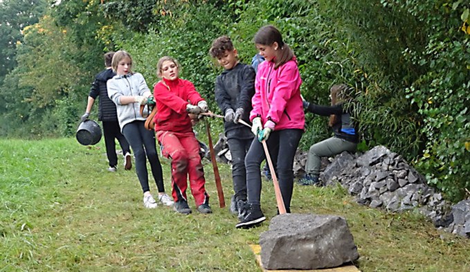 Mit einer Holzplatte transportierten die Schüler die schweren Steine.  (Foto zvg)